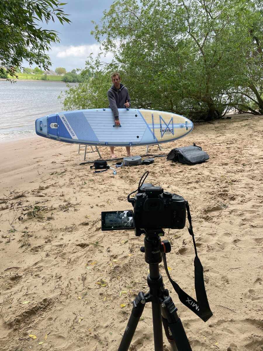 Steffen mit Kamera bei einer Aufnahme am Wasser